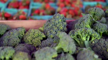 Ön planda brokoli ve arka planda çilek bulanıklığı ile sağa kaydır çiftçi pazarında.