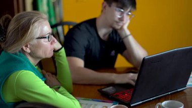 Odaklanmış bir anne ve dizüstü bilgisayarı açık bir şekilde okul hakkında konuşuyorlar..