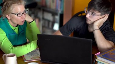 Anne ve genç oğul dizüstü bilgisayara bakarken okul hakkında konuşuyorlar..