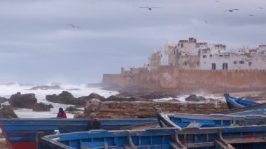 Fırtınalı bir günde Essaouira, Fas 'ın Atlantik Okyanusu' nun duvarlara çarpması ve balıkçı teknelerinin ön planda olması..