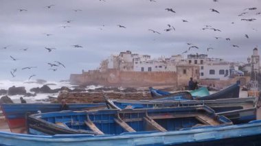 Fırtınalı bir günde Essaouira, Fas 'ta sörf yaparken ve ön planda balıkçı tekneleri varken..