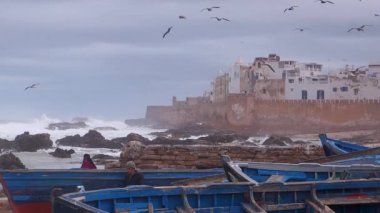 Fırtınalı bir günde Essaouira, Fas 'ın Atlantik Okyanusu' nun duvarlara çarpması ve balıkçı teknelerinin ön planda olması..