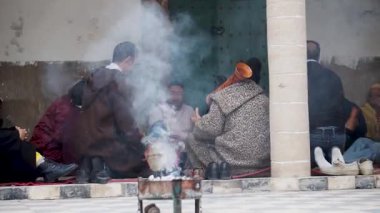 Tütsü dumanından, bateri çalan ve Fas, Essaouira 'da düzenlenen bir Sufi ayini sırasında şarkı söyleyen adamların düşük açılı çekimi..