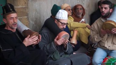 Sufi töreninde davul çalan ve Fas, Essaouira 'da ilahi söyleyen adamların yüksek açılı yakın çekimi.