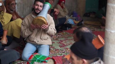 Erkekler Fas, Essaouira 'da bir sufi töreninde trampet çalıp şarkı söyleyerek transa geçiyorlar..