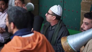 Geleneksel giyinmiş, şarkı söyleyen ve davul çalan erkeklerin Sufi seremonisi sırasında transa girmesi.