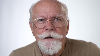 Yakışıklı, yaşlı bir adamın, beyaz arka planda kameraya bakarken gülümseyen portresi. İnsan duyguları ve yüz ifadeleri 