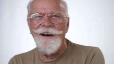 Yakışıklı, yaşlı bir adamın, beyaz arka planda kameraya bakıp gülen portresi. İnsan duyguları ve yüz ifadeleri 