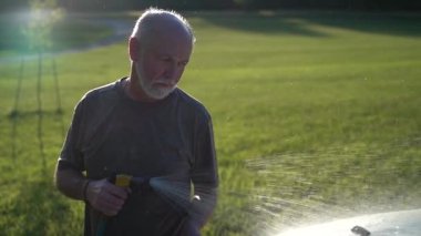 Depresyonlu kızgın bir adam arabanın üzerine su püskürtüyor. Depresyon konsepti olarak yerinde duruyor..