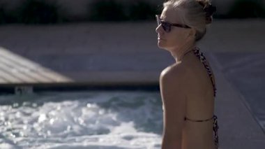 Dışarıda bir jakuzide omuzlarını esneten güzel, olgun bir kadının yakın çekimi..