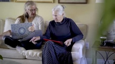 Laptop ve tablet bilgisayarlı iki güzel sarışın kadın oturma odasında tartışıp sohbet ediyorlar..