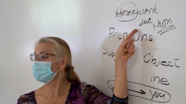 Gülümseyen olgun bir kadının yakından çekilmiş portresi. İngilizce öğretmeni, bir okul sınıfında beyaz tahtaya yaslanmış..