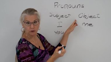 Gülümseyen olgun bir kadının yakından çekilmiş portresi. İngilizce öğretmeni, bir okul sınıfında beyaz tahtaya yaslanmış..