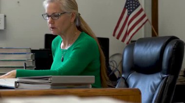 Masada çalışan, tıbbi maske takan ve masa başında PPE ve ABD bayrağı taşıyan öğretmenlerin yakınlaşması..