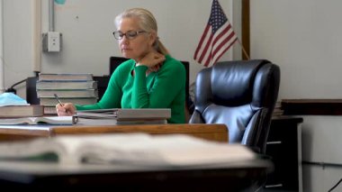 Masasında sağlık maskesi ve dezenfektanla çalışan öğretmen masada PPE ve ABD bayrağı arkasında..