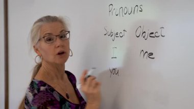 Gülümseyen olgun bir kadının yakından çekilmiş portresi. İngilizce öğretmeni, bir okul sınıfında beyaz tahtaya yaslanmış..