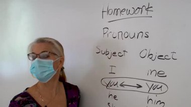 Gülümseyen olgun bir kadının yakından çekilmiş portresi. İngilizce öğretmeni, bir okul sınıfında beyaz tahtaya yaslanmış..