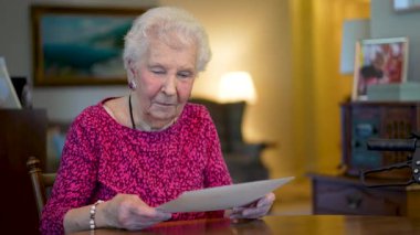 Masada oturan yaşlı yaşlı kadın fotoğraf hatıralarına bakıyor..
