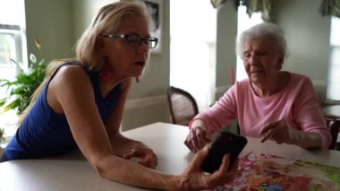 50 'li yaşlarda, 60' lı yaşlarda, elinde telefonla aile dostlarıyla kamerayla görüntülü konuşma yapan olgun bir kadın..