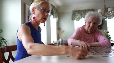 İki mutlu olgun kadının bulmaca parçalarıyla konuşup oynamalarının düşük açılı görüntüsü..