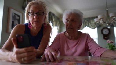 Mutlu el sallama ve olgun orta yaşlı kızıyla gülümseyen yaşlı kadın görüntüsü, telefonda görüntülü konuşma. Akıllı telefondan ailenle konuşurken gülümse..