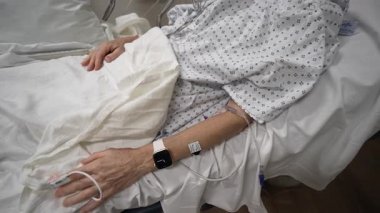 Winchester, VA, ABD - 09 03 2025: Olgun bir kadın, acil serviste tedavi görürken çeşitli tıbbi cihazlara bağlı olarak hastane yatağında dinleniyor.