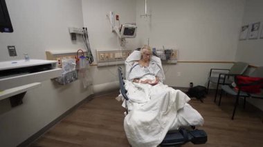 Winchester, VA, USA - 09 03 2025: A mature woman sits on a hospital bed in the emergency room, waiting for medical attention while surrounded by medical equipment and a calm environment.