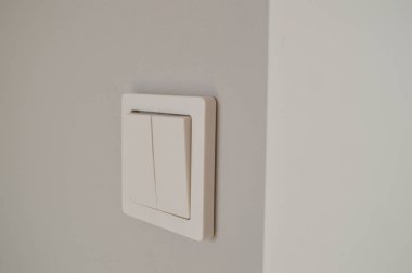 Temiz ve minimalist tasarımını vurgulayan beyaz bir duvar lambası. Görüntü, aydınlatmayı kontrol etmek için gerekli olan bu yaygın ev eşyasının işlevselliğini ve basitliğini vurgular.