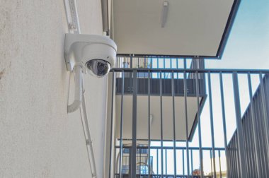Güvenlik kamerasıyla donatılmış bir apartman dairesi. Bölge sakinleri için gözetleme ve güvenliğin önemini vurguluyor. Kamera, genel olarak izleme ve koruma sağlar.