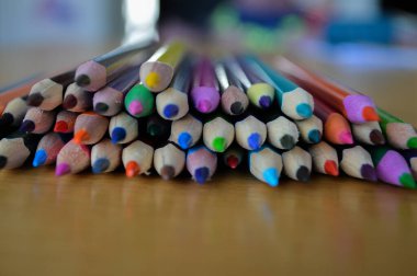 Sanat, çizim ve yaratıcı projeler için mükemmel bir şekilde çizim masasına dizilmiş renkli renkli kalemler. Sanatçılar, öğrenciler ve amatörler için ilham verici bir düzen..