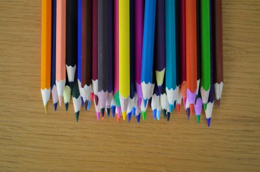 Sanat, çizim ve yaratıcı projeler için mükemmel bir şekilde çizim masasına dizilmiş renkli renkli kalemler. Sanatçılar, öğrenciler ve amatörler için ilham verici bir düzen..