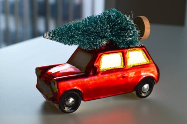 A charming New Year's ornament in the shape of a red car with a Christmas tree on its roof. This festive decoration can symbolize car insurance, purchasing a new vehicle, or simply the joy of holiday travels and traditions. Perfect for adding a nosta clipart