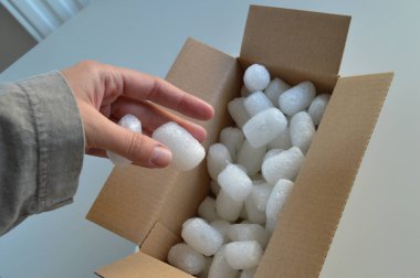 Koruyucu ambalaj malzemeleriyle dolu karton bir kargo kutusu, çevre dostu kağıt dolgu malzemesi ve biyolojik olarak çözünebilir fıstık paketleri de dahil. Bu malzemeler güvenli bir şekilde paketlemek, kırılgan eşyaları korumak ve güvenli bir şekilde teslim etmek için idealdir.