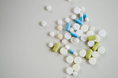 Farklı şekillerde, boyutlarda ve beyaz bir yüzeye dağılmış çeşitli ilaç hapları ve kapsüller. Bu tıbbi konsept sağlık, tedavi, reçeteli ilaçlar ve reçetesiz ilaçları temsil ediyor. Görüntü modayı simgeler