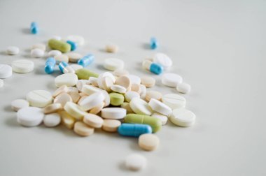 Farklı şekillerde, boyutlarda ve beyaz bir yüzeye dağılmış çeşitli ilaç hapları ve kapsüller. Bu tıbbi konsept sağlık, tedavi, reçeteli ilaçlar ve reçetesiz ilaçları temsil ediyor. Görüntü modayı simgeler