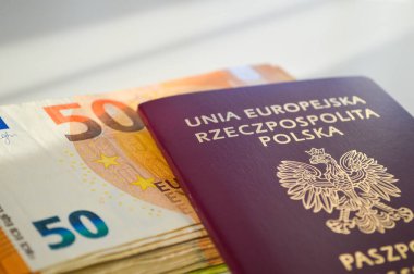 Polonya pasaportu bir yığın Euro banknotunun üzerine yerleştirilmiş, öncelikle 50 Euro 'luk banknotlar, beyaz bir masanın üzerine. Görüntü seyahat, mali güvenlik, uluslararası hareket kabiliyeti ve küresel fırsatları simgeliyor. İlgili temaları resmetmek için idealdir