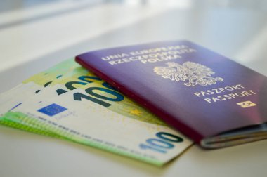 Polonya pasaportu bir yığın Euro banknotunun üzerine yerleştirilmiş, öncelikle 50 Euro 'luk banknotlar, beyaz bir masanın üzerine. Görüntü seyahat, mali güvenlik, uluslararası hareket kabiliyeti ve küresel fırsatları simgeliyor. İlgili temaları resmetmek için idealdir