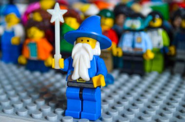 Sihirli bir Lego sihirbazı figürü ön planda güvenle duruyor ve bulanık, küçük figürlere odaklanıyor. Bireysellik, liderlik ve fantezi kavramı