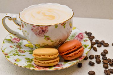 Çok güzel dizayn edilmiş, kremalı kahveyle dolu bir çay fincanı. Yanında da çiçekli bir çay tabağı. Dağınık kahve çekirdekleri sıcacık ve aromatik atmosfere ekleniyor. Bu zarif kompozisyon rel 'in özünü yakalar