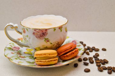 Çok güzel dizayn edilmiş, kremalı kahveyle dolu bir çay fincanı. Yanında da çiçekli bir çay tabağı. Dağınık kahve çekirdekleri sıcacık ve aromatik atmosfere ekleniyor. Bu zarif kompozisyon rel 'in özünü yakalar