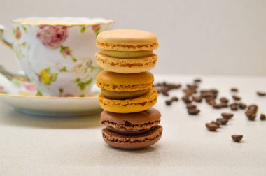 Dağınık kahve çekirdekleri ile çevrili eski bir çiçek fincanına karşı yapılmış renkli bir demet kurabiye. Tatlılığın ve entelektüelliğin mükemmel bir karışımı, samimi bir kafe anın sıcaklığını çağrıştırıyor..