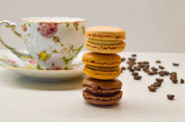 Dağınık kahve çekirdekleri ile çevrili eski bir çiçek fincanına karşı yapılmış renkli bir demet kurabiye. Tatlılığın ve entelektüelliğin mükemmel bir karışımı, samimi bir kafe anın sıcaklığını çağrıştırıyor..