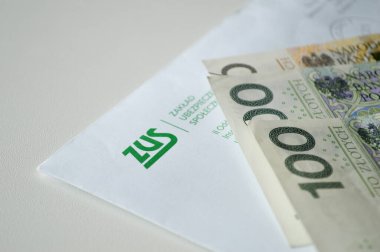 Polonya Sosyal Sigorta Kurumu ile birlikte ZUS 'tan (Zaklad Ubezpieczen Spolecznych - Polonya Sosyal Sigorta Kurumu) gelen bir zarfı gösteren yakın plan bir resim (100 zloti). Bu görsel sosyal güvenlik ödemeleri, emekli aylıkları, hükümet Ben kavramını temsil eder