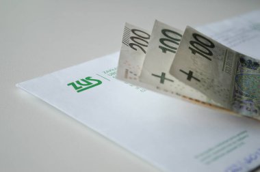 Polonya Sosyal Sigorta Kurumu ile birlikte ZUS 'tan (Zaklad Ubezpieczen Spolecznych - Polonya Sosyal Sigorta Kurumu) gelen bir zarfı gösteren yakın plan bir resim (100 zloti). Bu görsel sosyal güvenlik ödemeleri, emekli aylıkları, hükümet Ben kavramını temsil eder