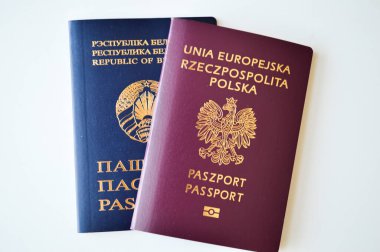 Polonya pasaportu ve Belarus pasaportunun temiz beyaz arka planda yan yana yattığı yakın plan bir görüntü. Bu fotoğraf uluslararası seyahat, çifte vatandaşlık, göç, sınır geçişi ve kimlik belgelerini temsil ediyor. Tam benlik.