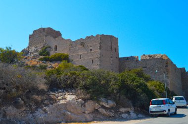 Yunanistan 'ın Rodos kentindeki antik Monolithos Şatosu' nun bir bölümünde, bu resim, arka planda Ege Denizi 'ni ve kıyı şeridini süpüren bereketli bir ormanın üzerinde duran kalenin yıpranmış taş duvarlarını yakalıyor. S Şövalyeleri tarafından inşa edildi.