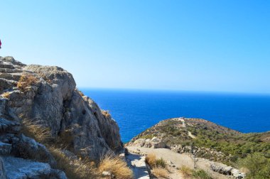 Yunanistan 'ın Rodos kentindeki antik Monolithos Şatosu' nun bir bölümünde, bu resim, arka planda Ege Denizi 'ni ve kıyı şeridini süpüren bereketli bir ormanın üzerinde duran kalenin yıpranmış taş duvarlarını yakalıyor. S Şövalyeleri tarafından inşa edildi.