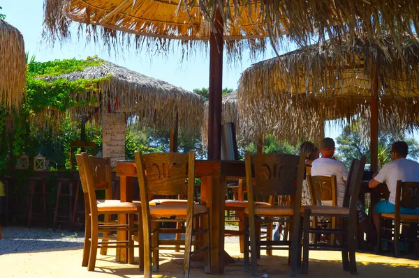 Sazdan yapılmış şemsiyelerden ve yemyeşil sarmaşıklardan oluşan bir gölgeliğin altına gizlenmiş bu kır barı, sizi gölgeli dinginliğinde gevşemeye davet ediyor. Tahta sandalyeler ve yüksek tabureler, sallanan bir tomarda el yazısıyla yazılmış kokteyl spesiyalleri, bir his uyandırıyor.