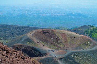 İtalya 'nın Sicilya kentindeki Etna Dağı' nın volkanik yamaçlarının manzarası. Siyah lav kayaları, seyrek bitki örtüsü ve canlı mavi gökyüzü patlamalarla şekillenen dramatik bir doğal manzara yaratır..