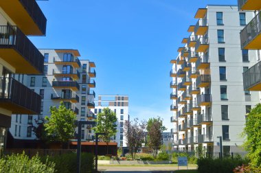 Temiz bir gökyüzünün altında canlı balkonları olan modern yerleşim tesislerinin dinamik görüntüsü. Varşova 'da aktif gayrimenkul gelişimini ve yeni yaşam fırsatlarını yansıtıyor.